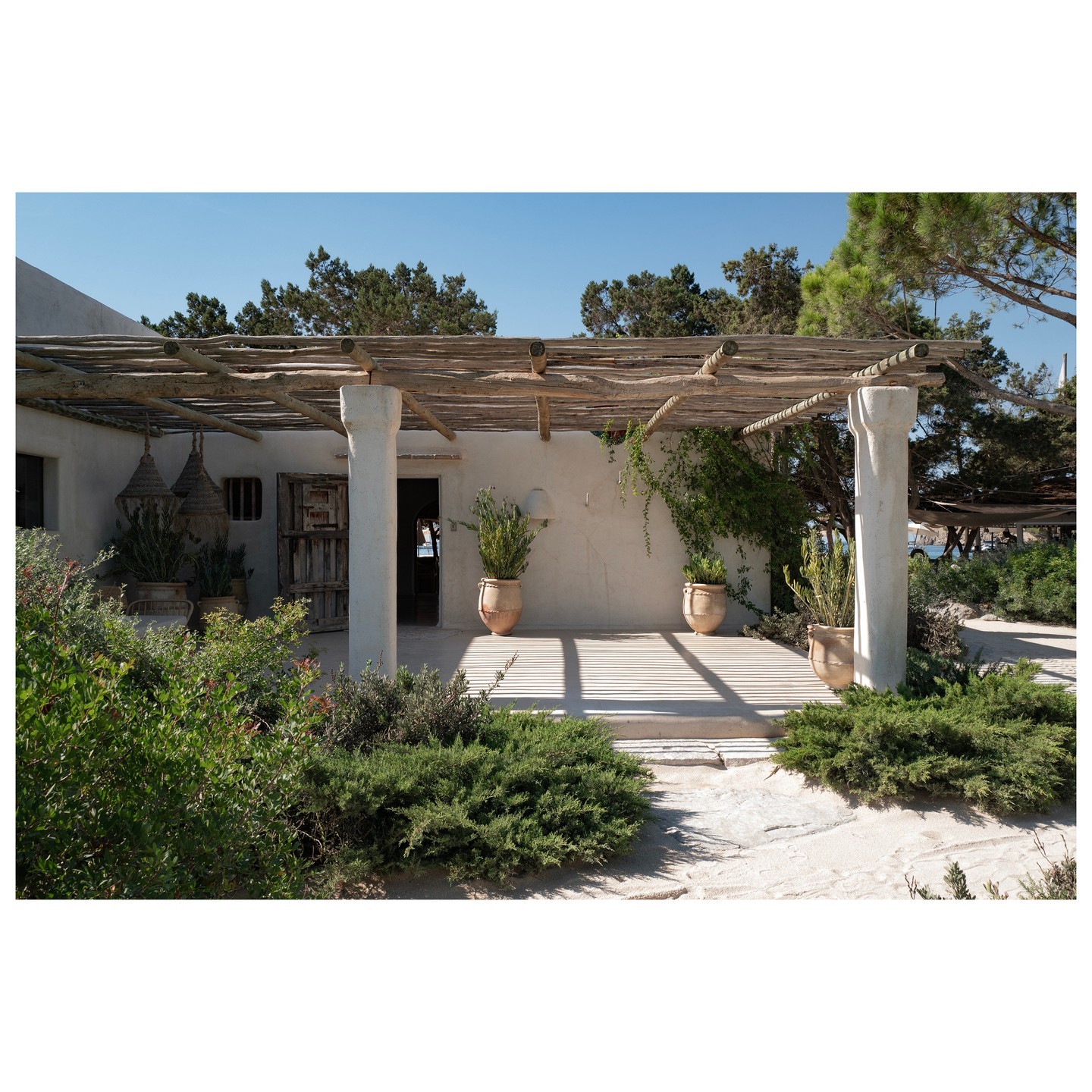 Hermosa terraza de Casa Jondal, con una pérgola rústica y plantas que crean una atmósfera relajante y mediterránea en el entorno natural.