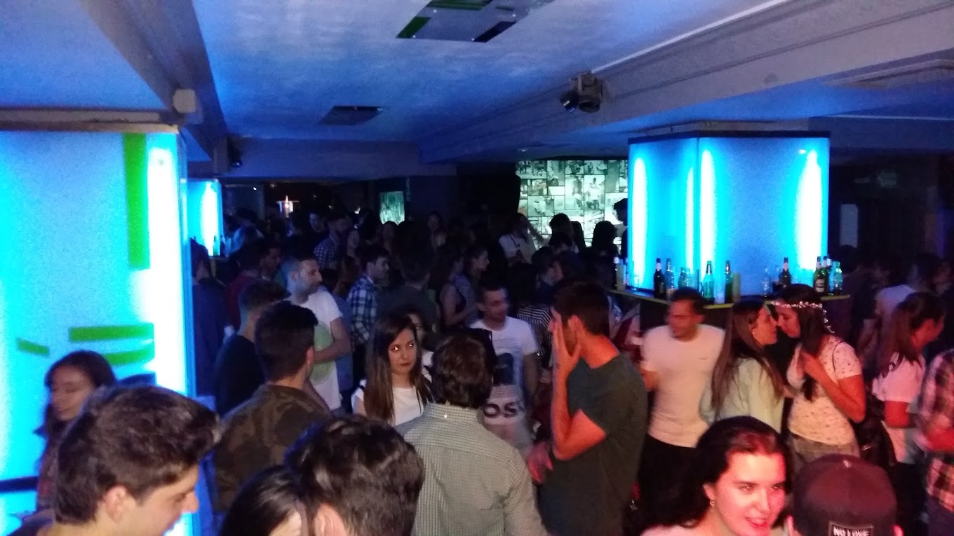 Ambiente animado en Bisu con iluminación azul neón, barra llena y asistentes disfrutando de una noche vibrante.