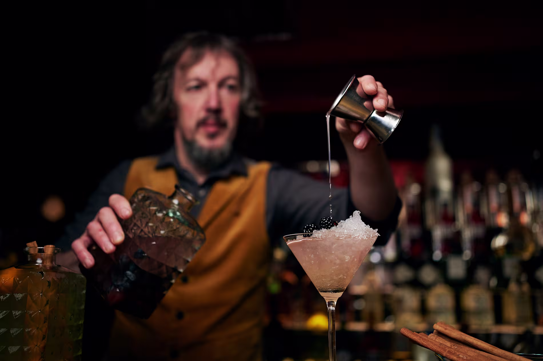 Un camarero de Clandestino vertiendo una bebida desde una coctelera en una copa de martini.