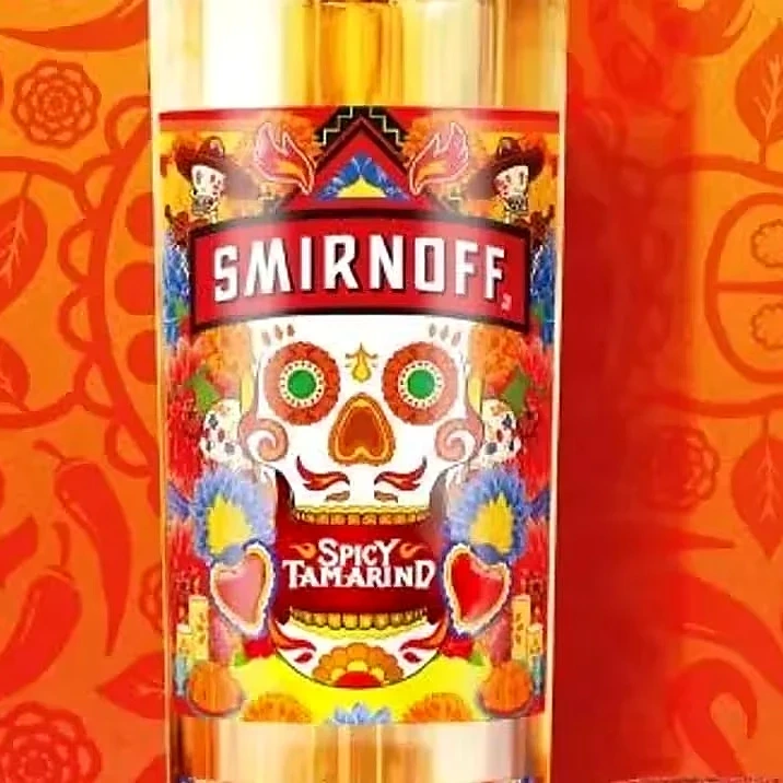 Botella de Smirnoff Spicy Tamarind sobre un fondo naranja con calaveras ilustradas