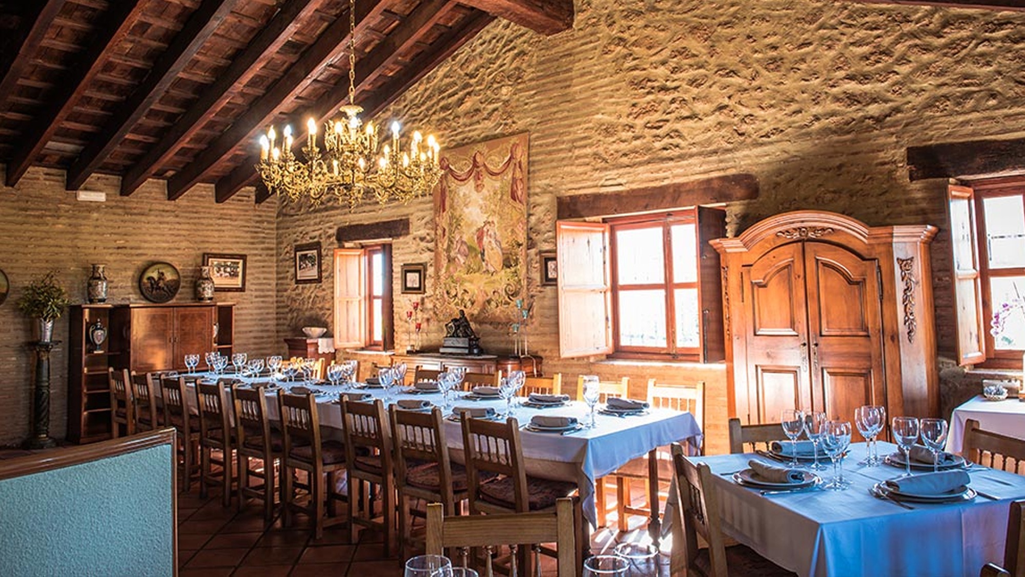 Una sala luminosa de esencia rústica, con techos de madera, tapices clásicos y una gran mesa que invita a celebrar alrededor de la buena mesa.