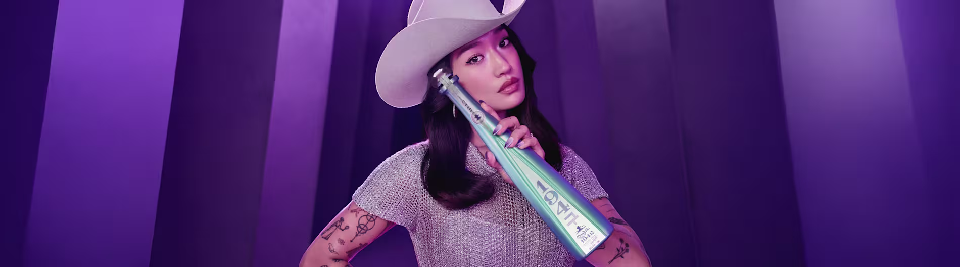 Peggu Gou holding a limited-edition Don Julio 1942 tequila bottle in a vibrant purple set