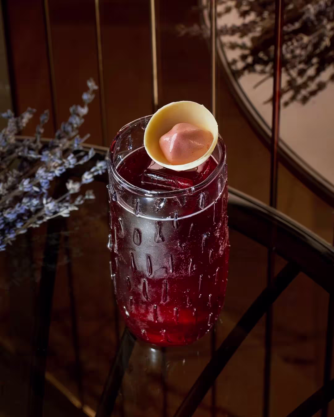 Un cóctel elegante en Jacqueline, servido en un vaso texturizado y adornado con un toque de chocolate blanco que refleja la sofisticación del lugar.