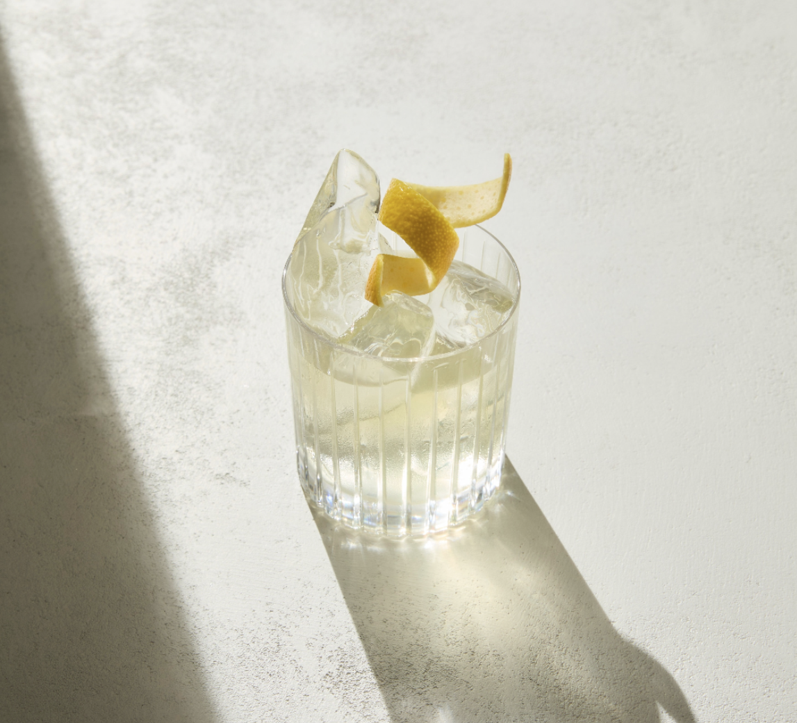 Egy tequila negroni egy asztalon, csavart citromhéjjal díszítve.