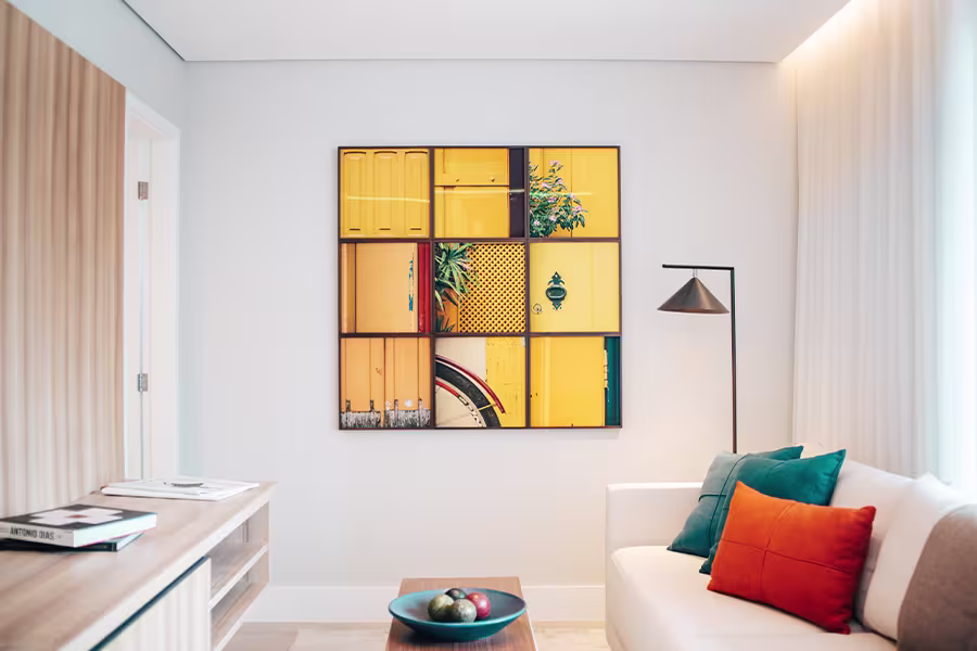 Modern living room with a white sofa, colorful cushions, a wooden coffee table, and a large yellow abstract artwork on the wall.