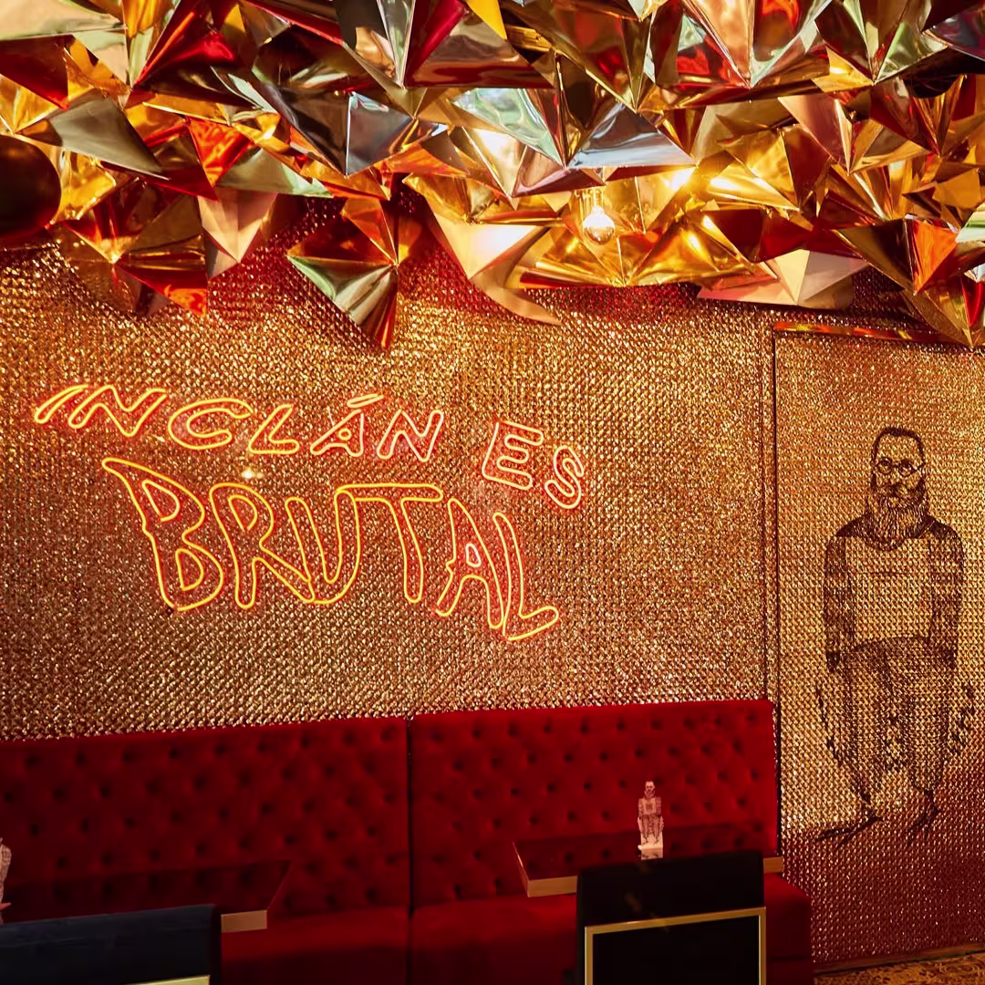 En Inclán Brutal Bar, paredes doradas reflejan un estilo extravagante, con sofás rojos y un letrero de neón que declara su brutalidad.