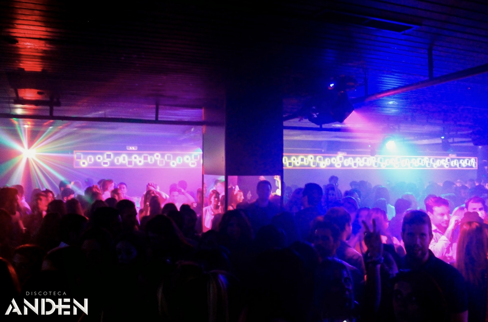 Pista de baile de la Discoteca Andén, con iluminación de colores vibrantes, música en vivo y una multitud disfrutando de la noche.