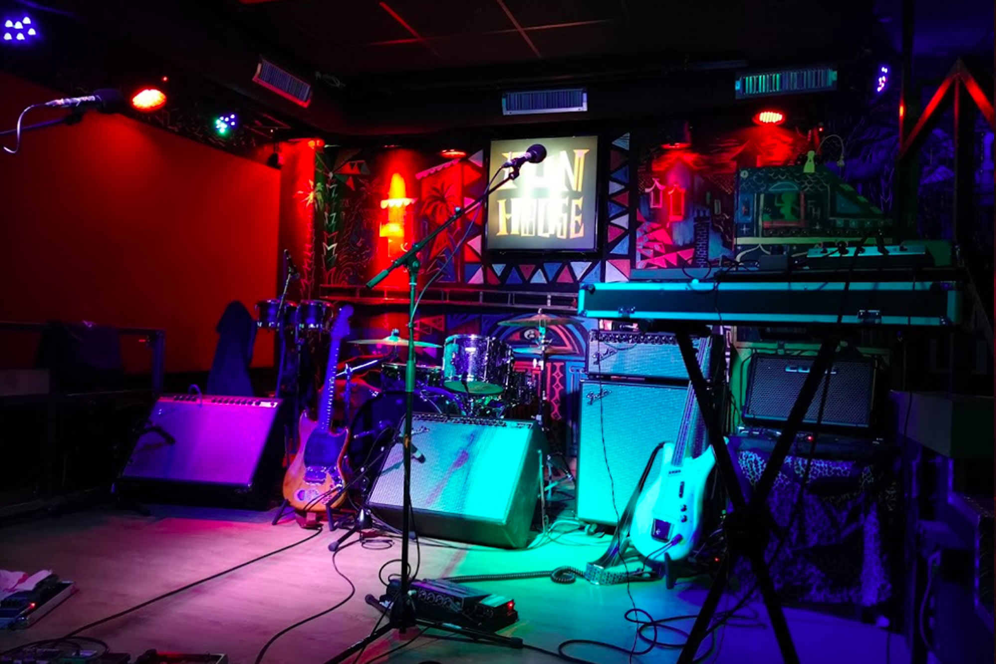 Fun House es un vibrante local de música en vivo con escenario colorido, instrumentos listos y luces que crean una atmósfera eléctrica