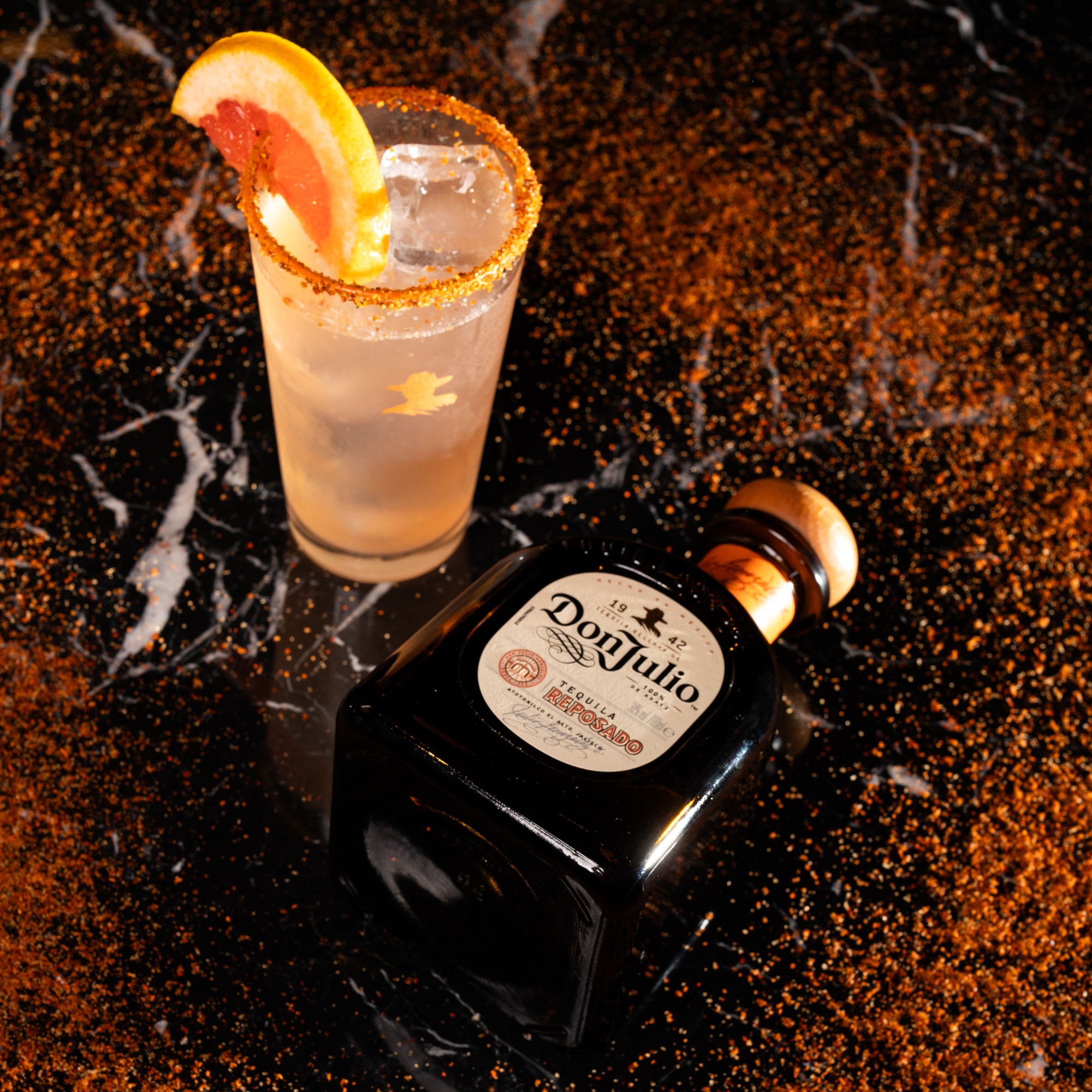 A Paloma cocktail with a grapefruit garnish next to a bottle of Don Julio