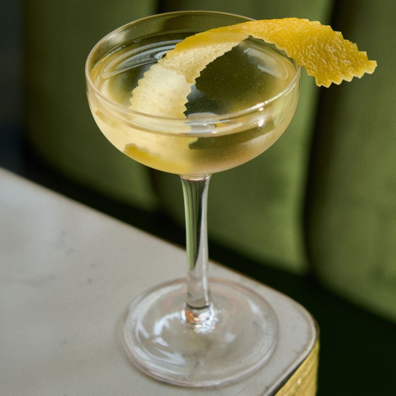 Vodka martini garnished with lemon peel set on the corner of a countertop