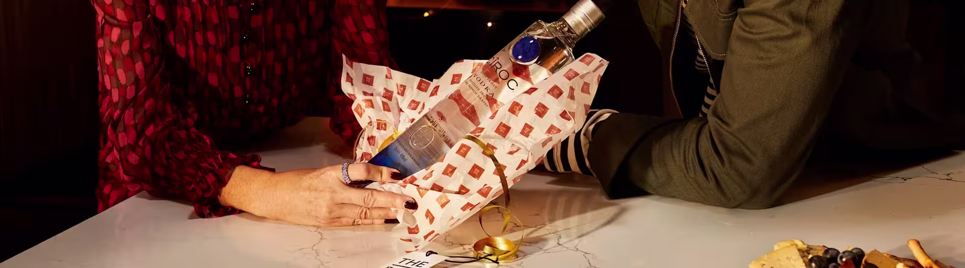 El vodka Cîroc envuelto en papel de seda con la marca, como si fuera un regalo, rodeado de un empaque festivo