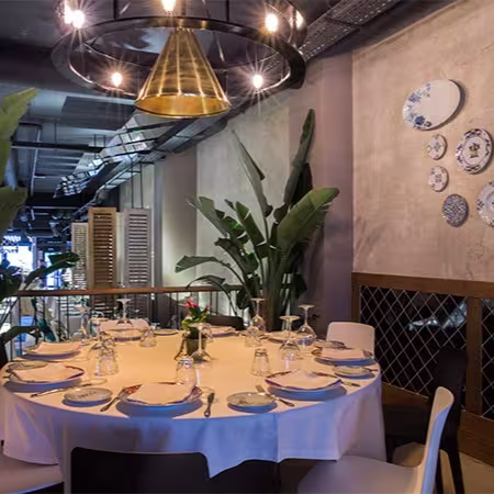 El Barril de las Cortes presenta una mesa redonda elegantemente dispuesta, rodeada de decoración sofisticada y detalles que evocan calidez y estilo.