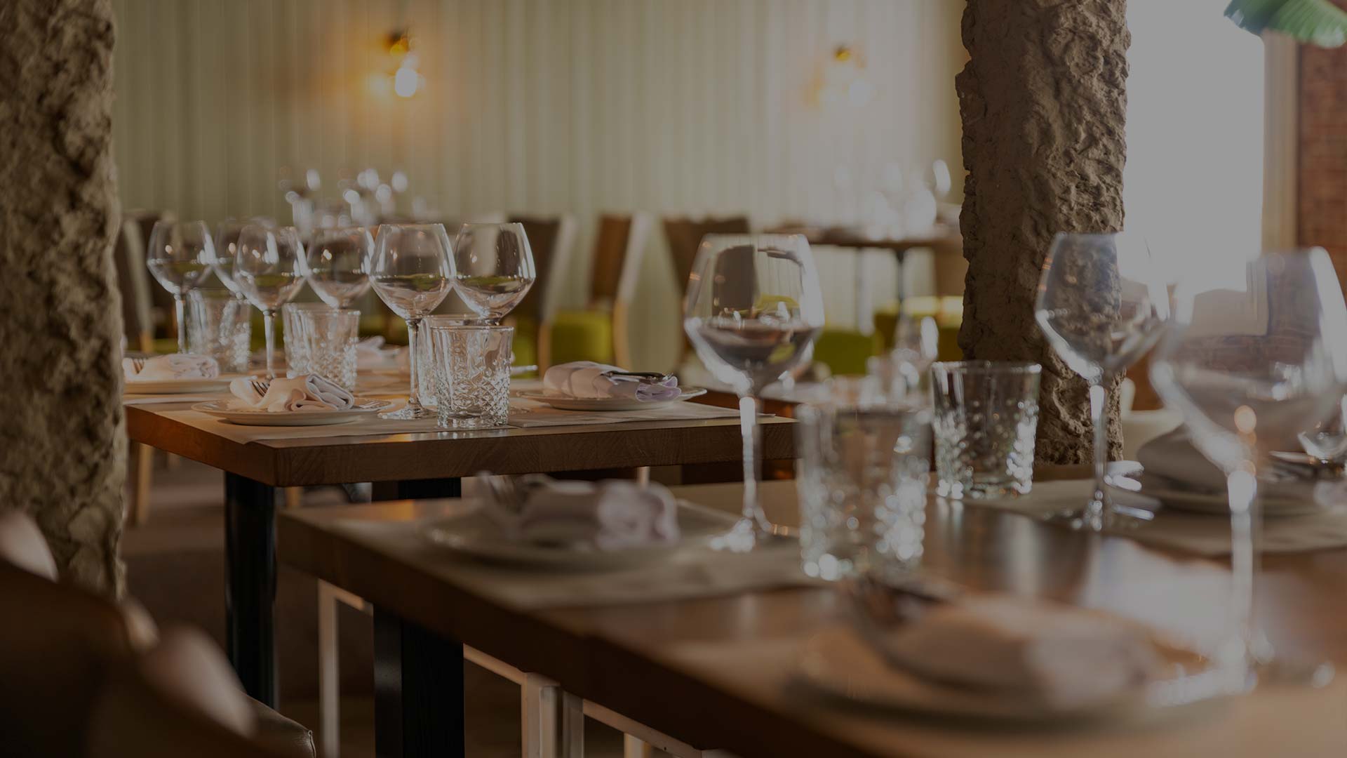 La imagen muestra una configuración de comedor de la Taberna Los Gallos. Hay una mesa larga con múltiples cubiertos, incluyendo platos, vasos y cubiertos.