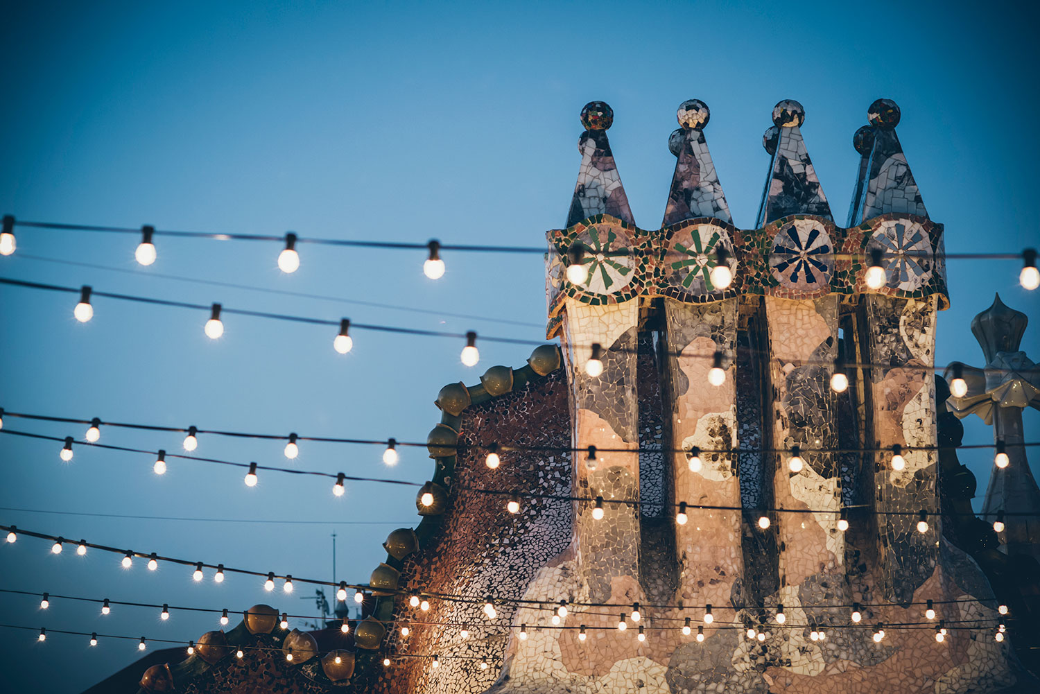 Las chimeneas icónicas de Casa Batlló iluminadas por guirnaldas crean un ambiente mágico y artístico en una noche inolvidable en Barcelona.