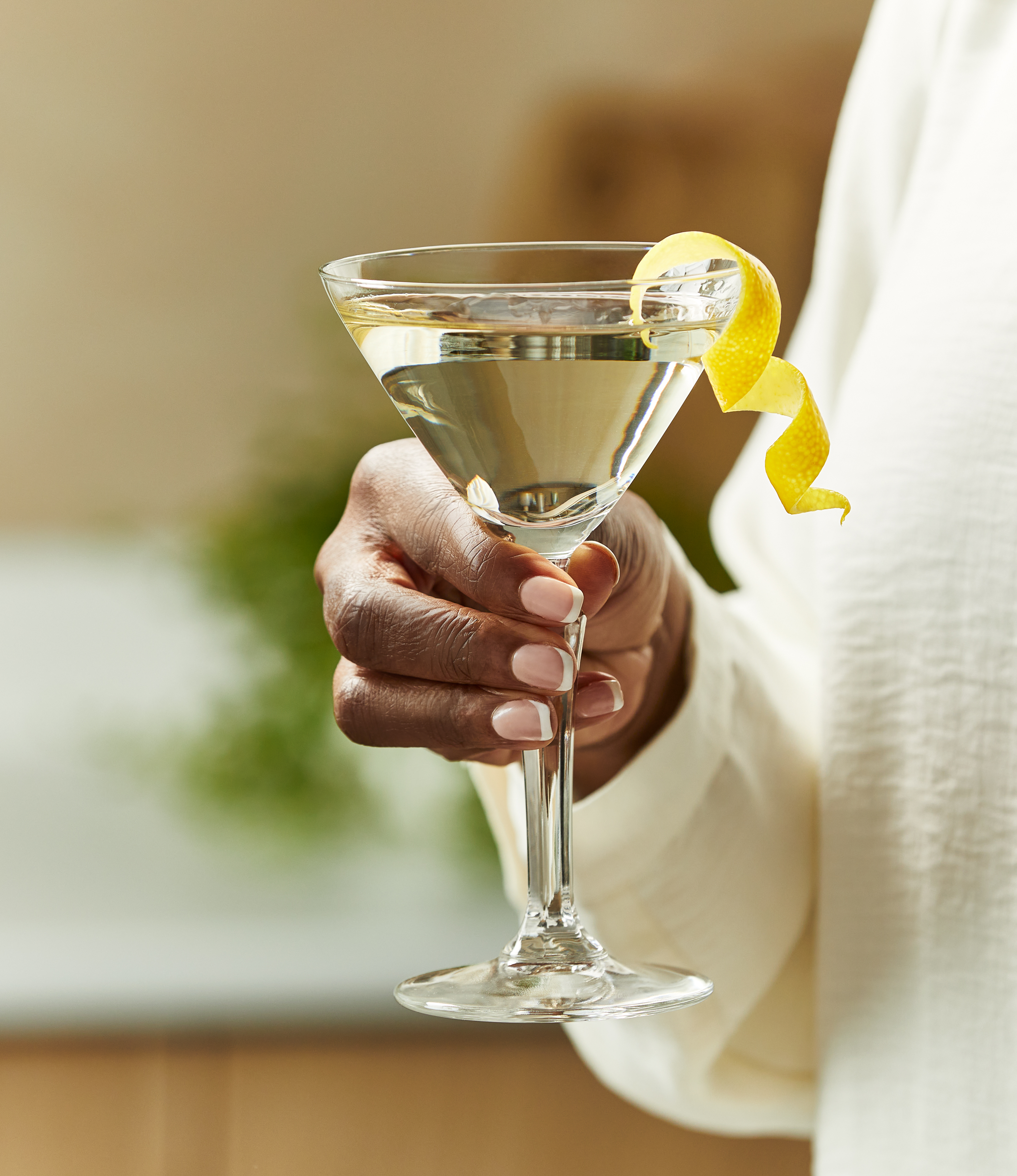A woman holds a Vesper martini with a lemon peel curl garnish