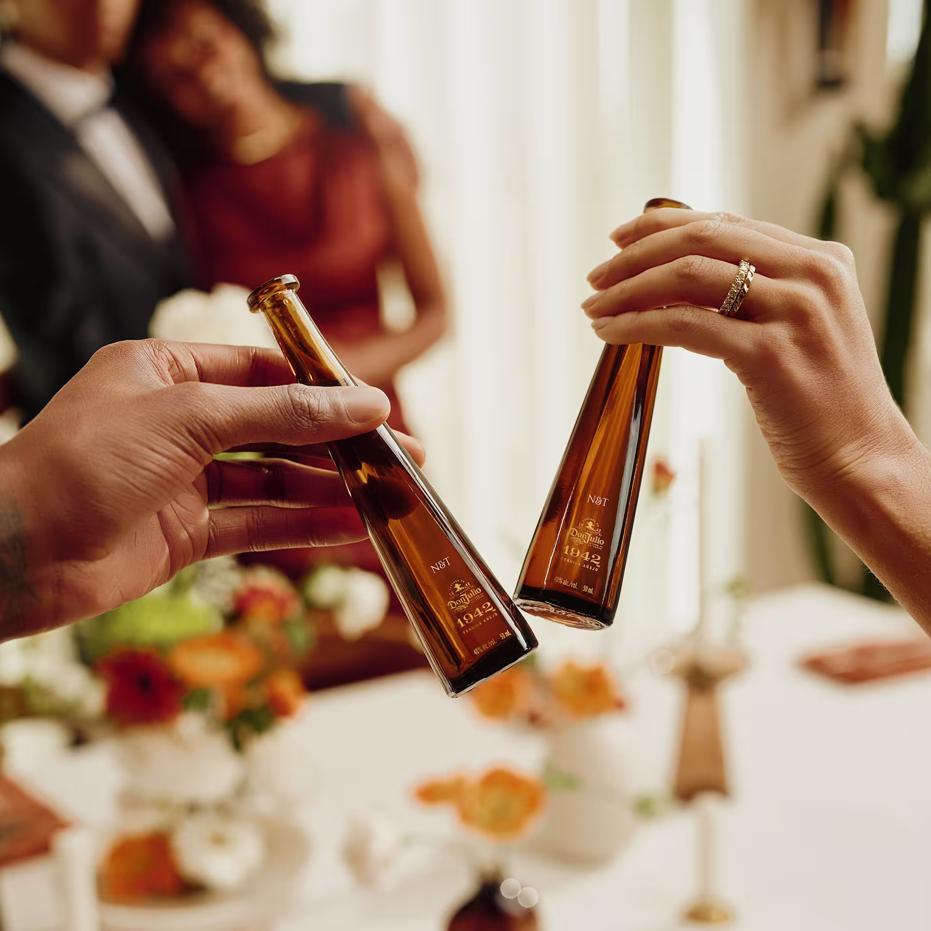 People toasting at a wedding with engraved bottles of Don Julio 1942
