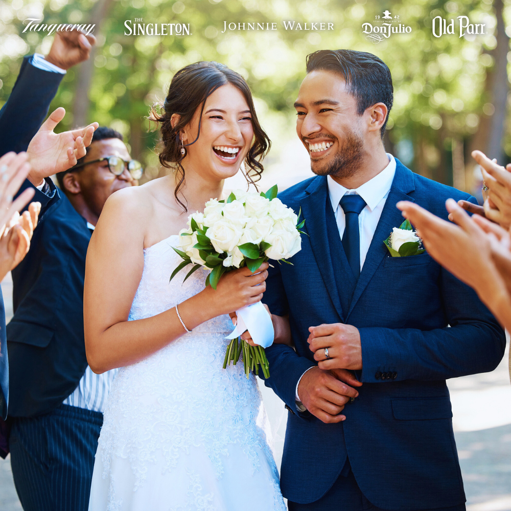 Novios felices celebrando su boda al aire libre, rodeados de invitados que les aclaman, con los logotipos de Tanqueray, The Singleton, Johnnie Walker, Don Julio y Old Parr en la parte superior.