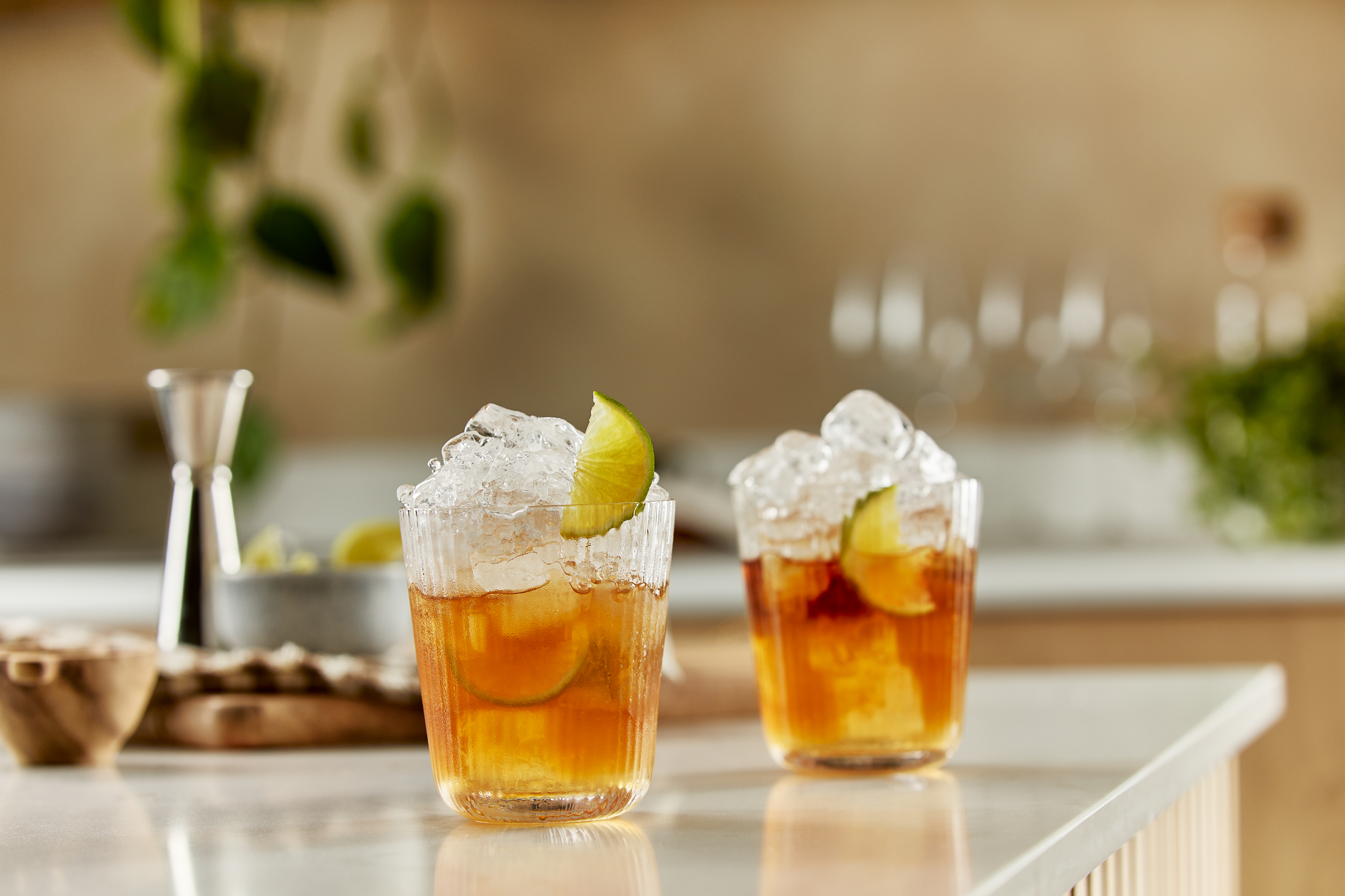 Two rum Caipirinha cocktails sit on a kitchen counter