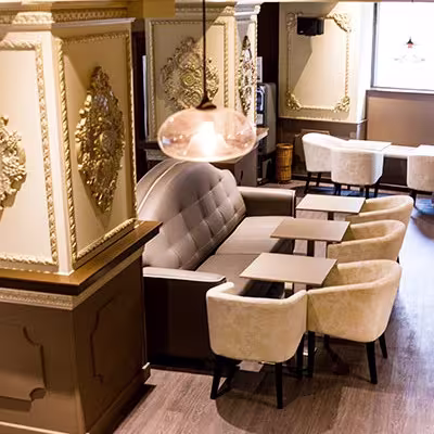 The New Salón del Café: Un ambiente elegante y clásico con detalles decorativos dorados y un mobiliario cómodo, ideal para disfrutar de una experiencia de café con estilo.
