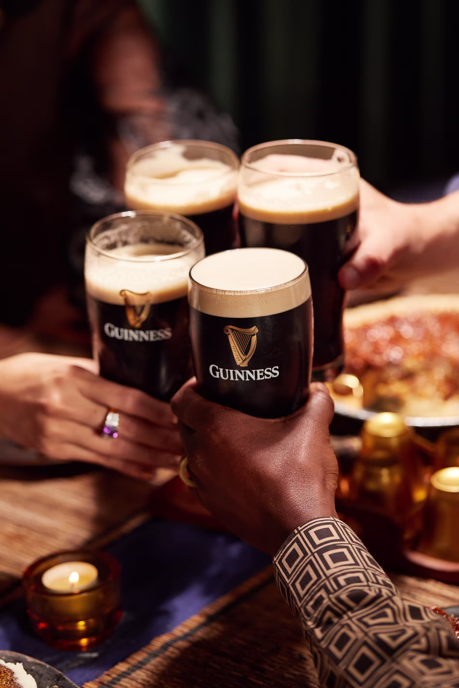 Group of friends toasting with pints of Guinness stout at a table