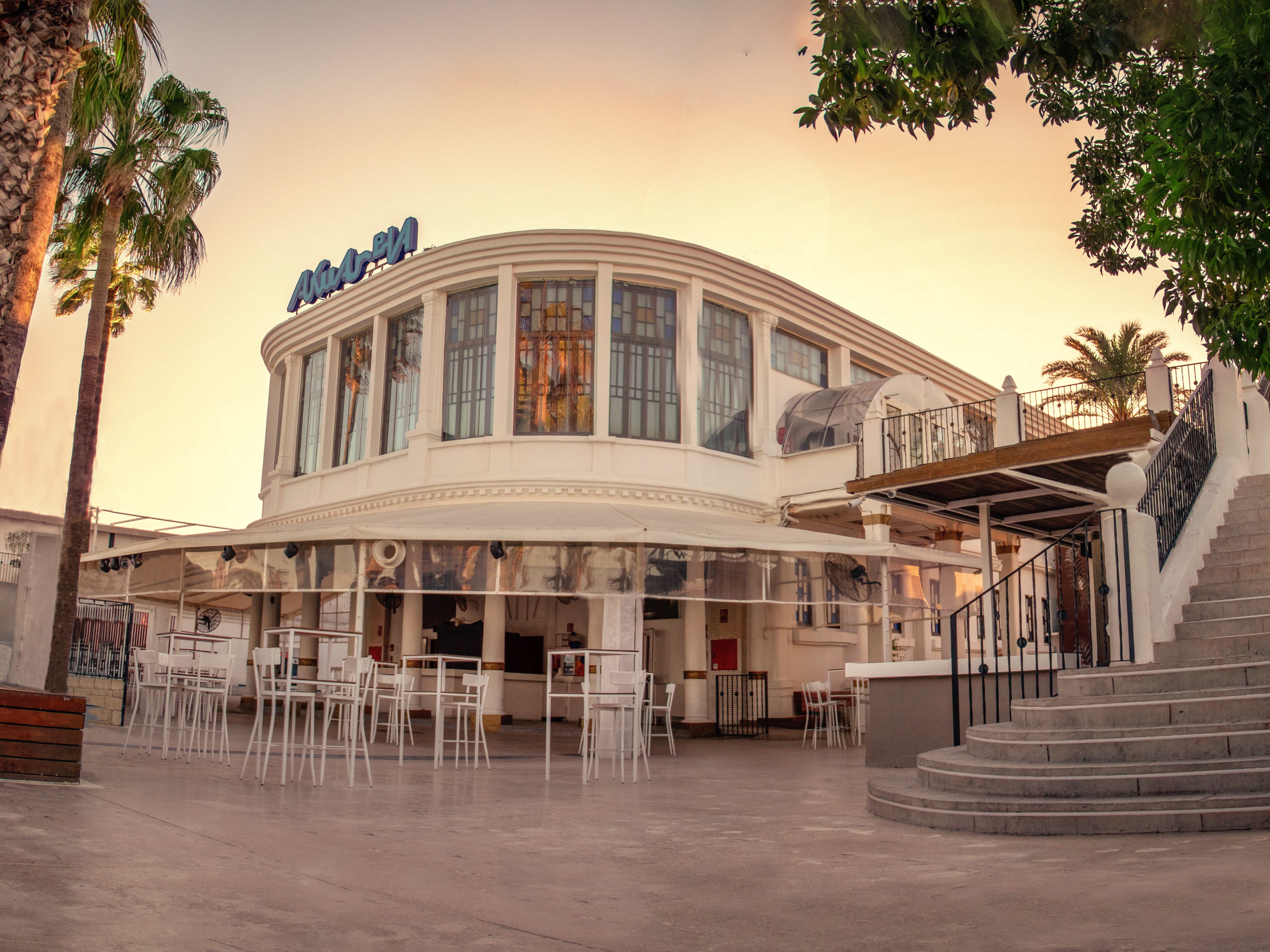 The Bar | Akuarela - Vista exterior de Akuarela durante el día, con palmeras y escaleras que conducen a la entrada del club.