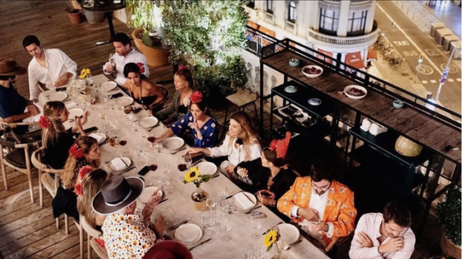La foto muestra un grupo de personas sentadas en una mesa larga con vistas en Casa Luz. Hay platos, vasos y centros de mesa florales en la mesa.