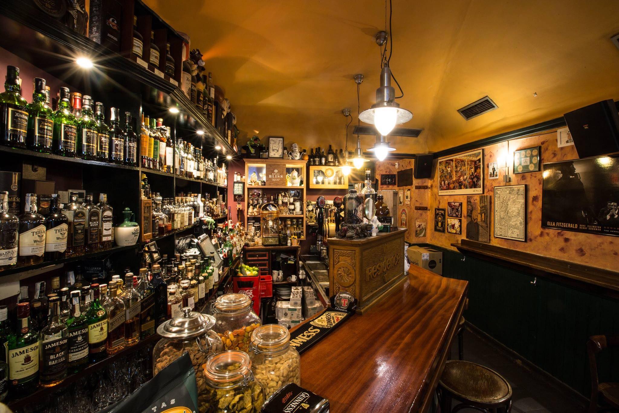 Pub Residence ofrece un ambiente acogedor con una barra de madera, estanterías repletas de botellas y decoración clásica llena de personalidad.