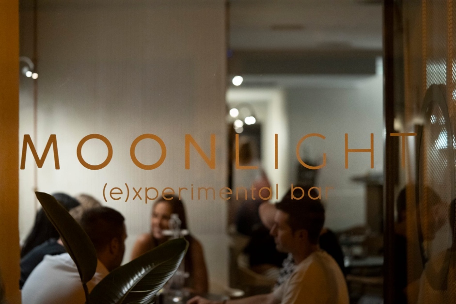 The Bar | Moonlight Experimental Bar - Primer plano de un cóctel elegante acompañado de un postre en un entorno minimalista.