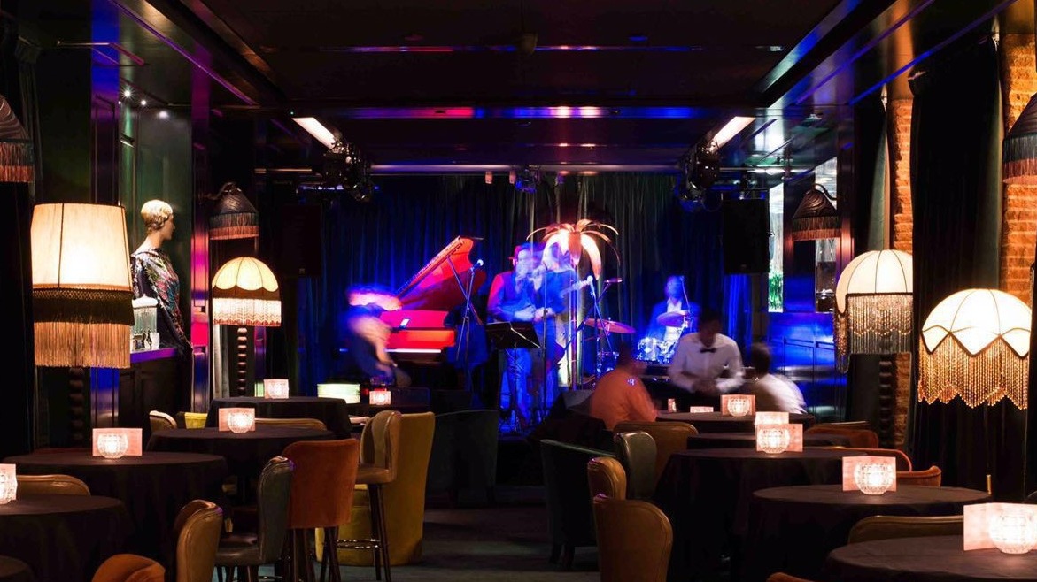 Amazónico ofrece un ambiente elegante con mesas iluminadas y una banda de jazz tocando en el escenario, creando una atmósfera sofisticada.