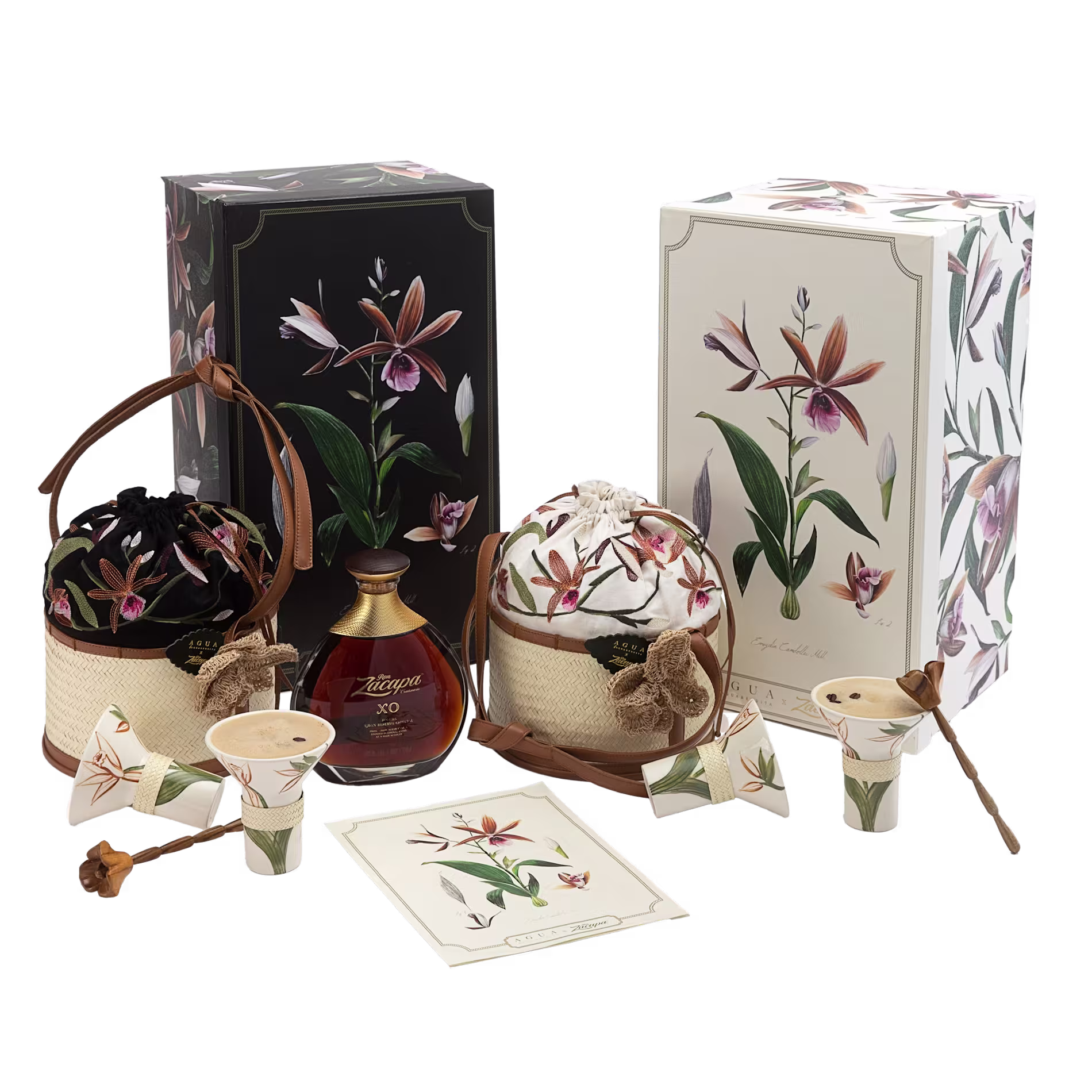 Assorted luxury gift items, including a bottle of Zacapa XO rum, floral print boxes, woven containers, cone cups, and a card with botanical illustrations.