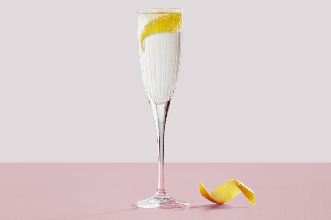 A French 76 cocktail in a Champagne flute with a twisted lemon peel