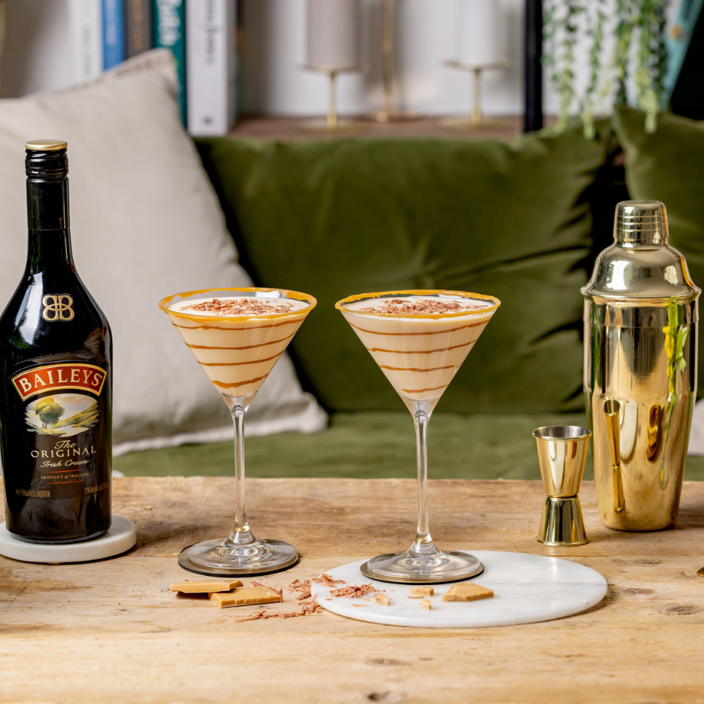Două Baileys Salted Caramel Espresso Martini lângă o sticlă de Baileys Original Irish Cream.