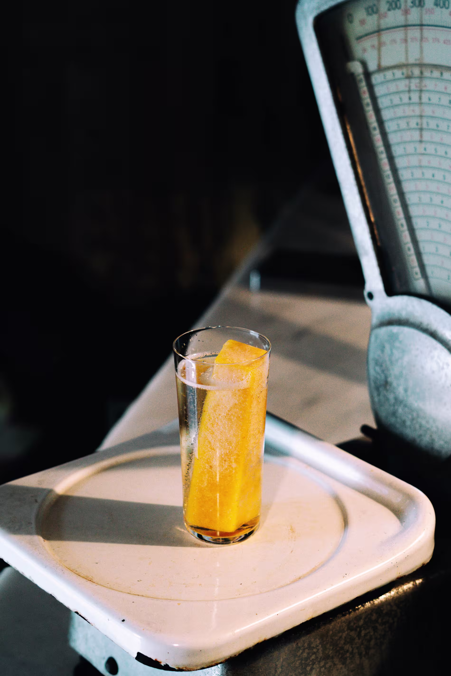 Cóctel en Niebla con hielo y toque de naranja servido sobre una balanza antigua. Estética industrial y minimalista con luz suave.