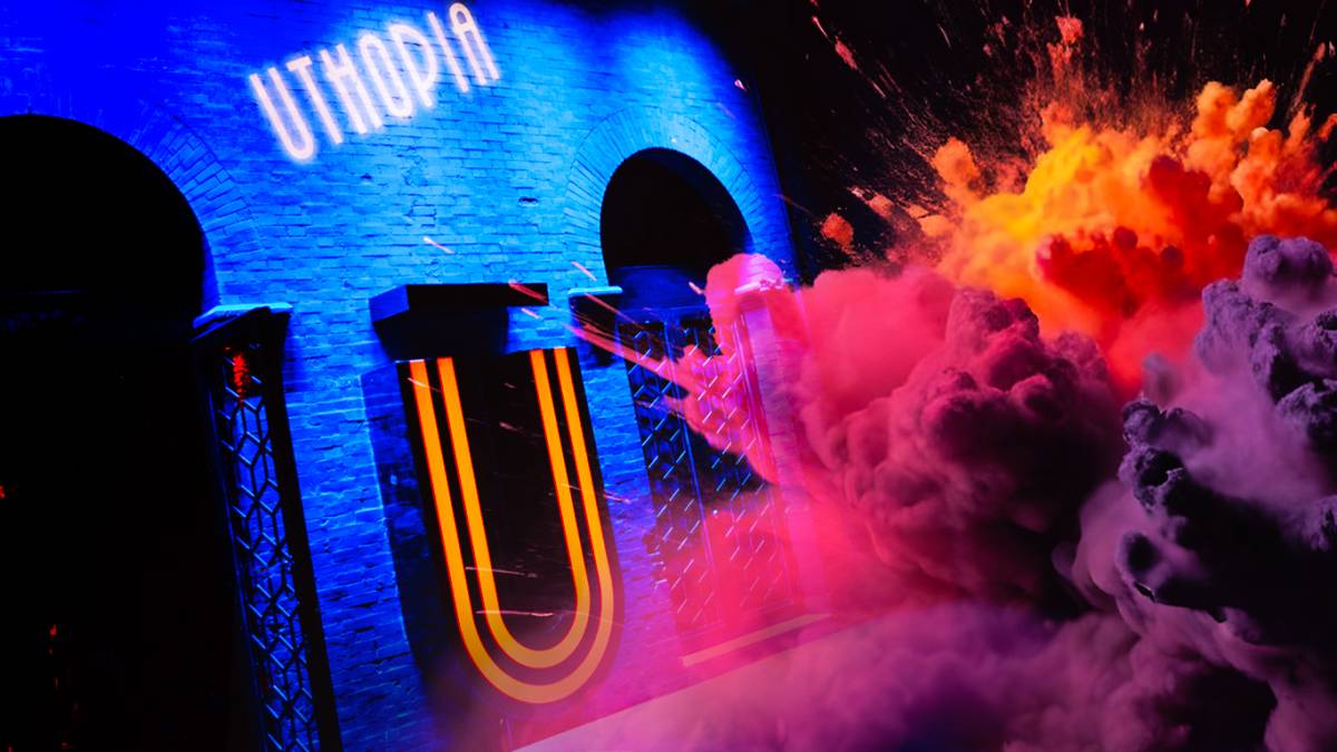 Fachada iluminada de Uthopia con colores vibrantes, detalles modernos y un ambiente lleno de energía y creatividad.