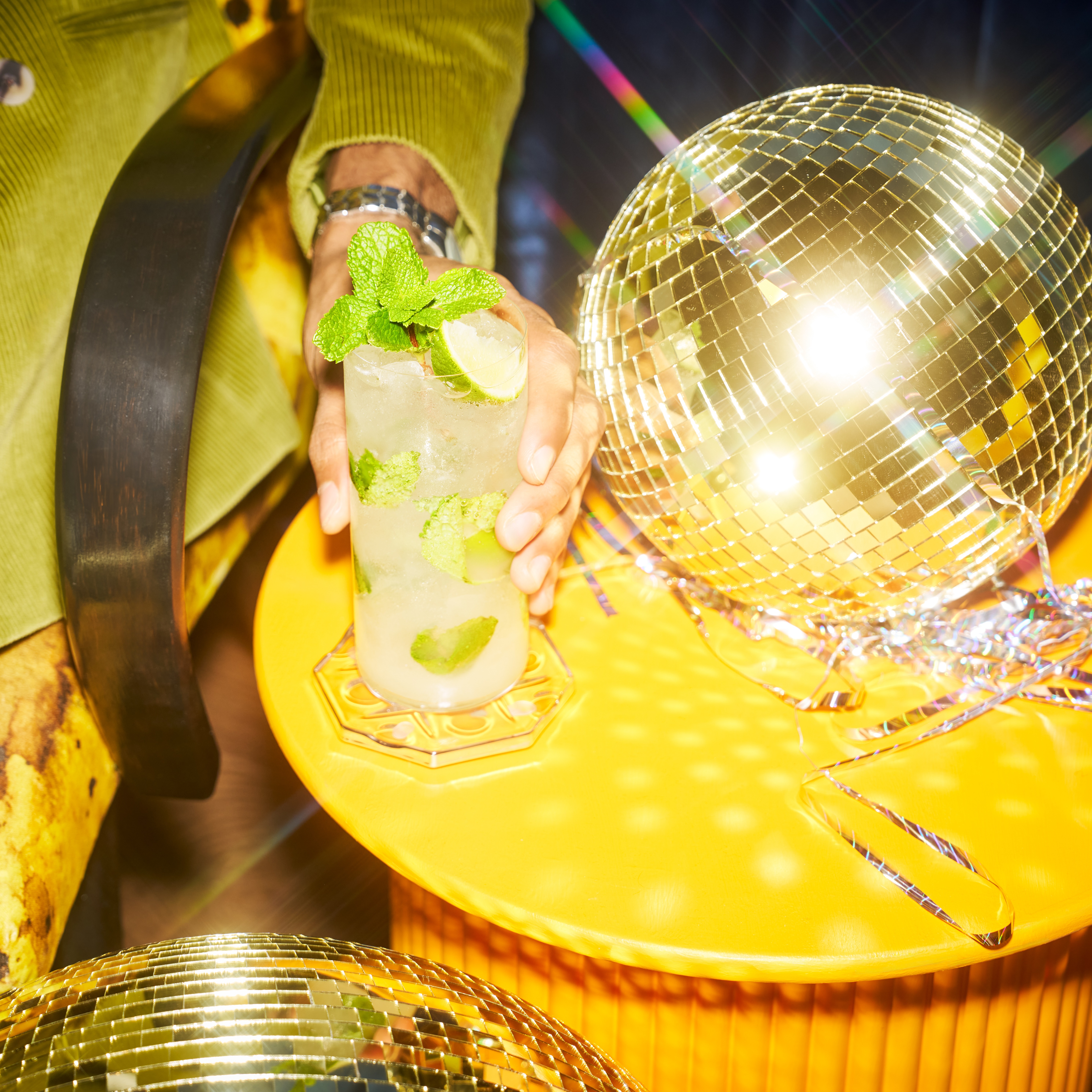 A mojito cocktail next to a disco ball