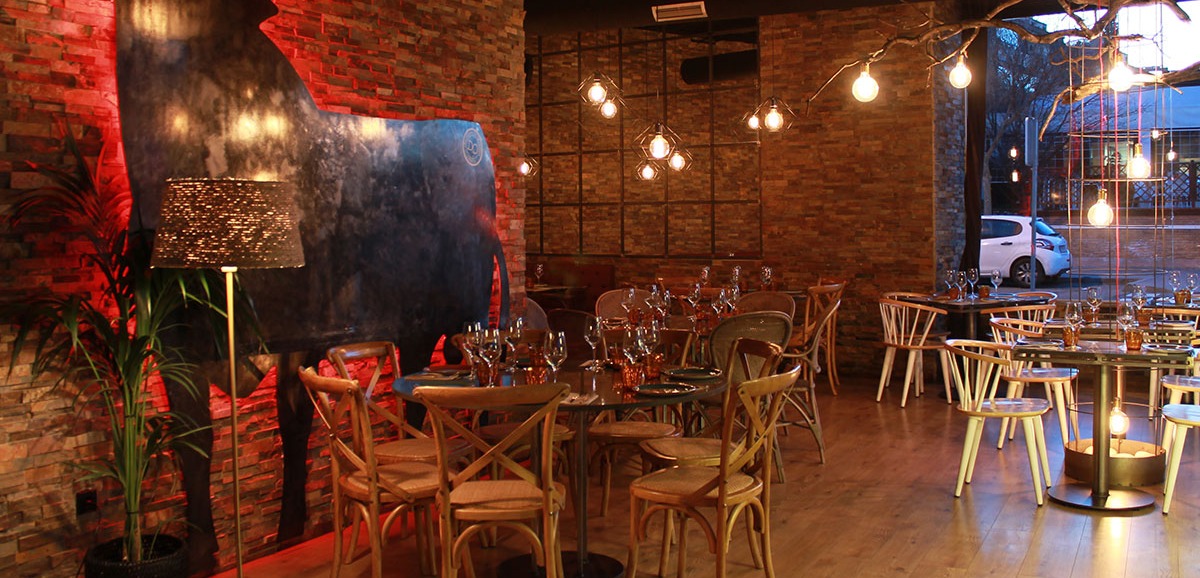 Espacio decorado con paredes de ladrillo, una figura de toro iluminada y muebles de madera que crean un ambiente acogedor y cálido
