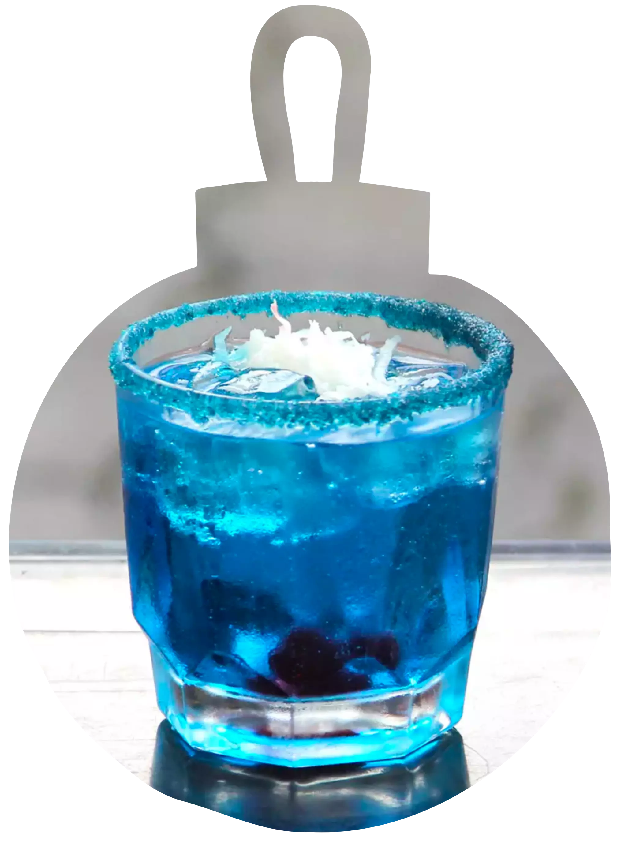 A glass of blue cocktail with ice, blue sugar rim, white flakes on top, and cherries at the bottom, placed on a reflective surface.