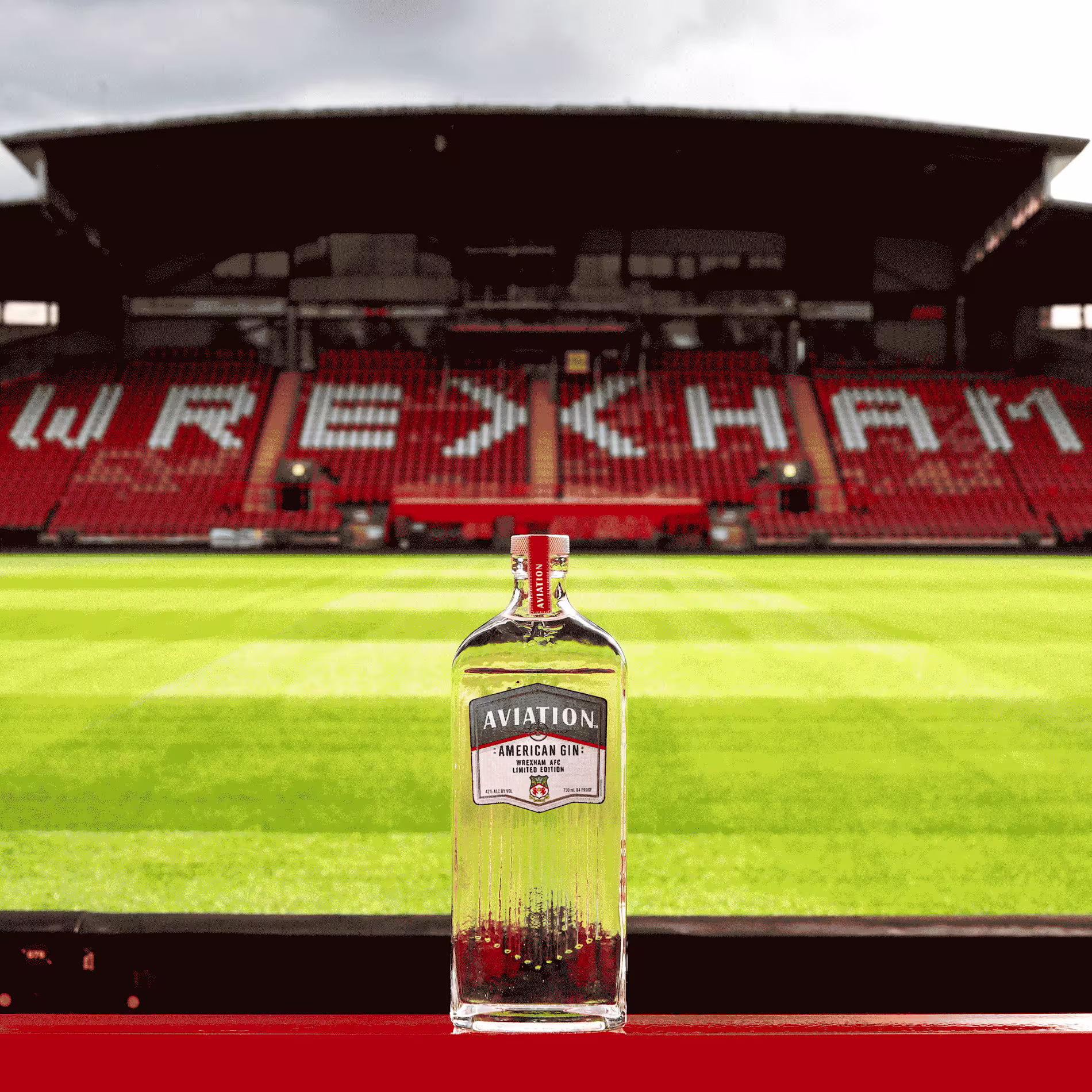 A bottle of Aviation American Gin is placed in front of empty seats at Wrexham AFC’s football stadium.