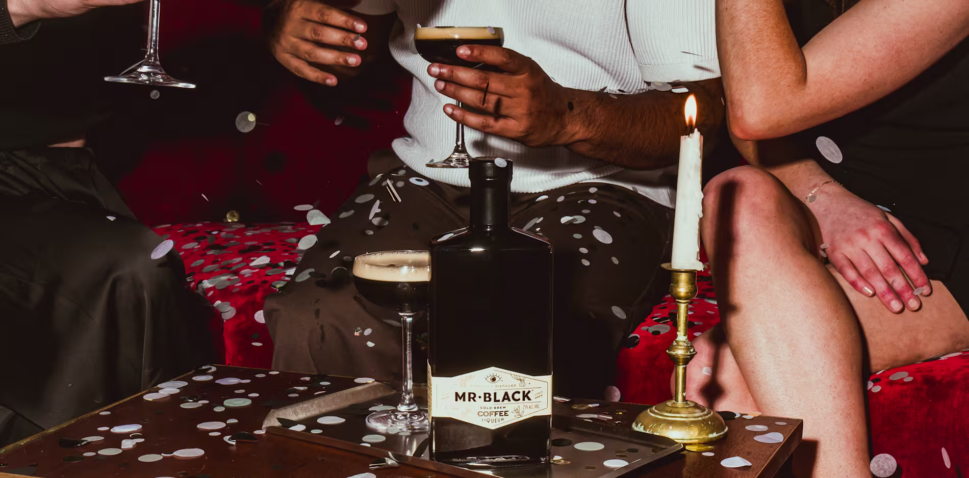 Group of friends celebrating with Mr Black espresso martini cocktails and confetti at a lively party