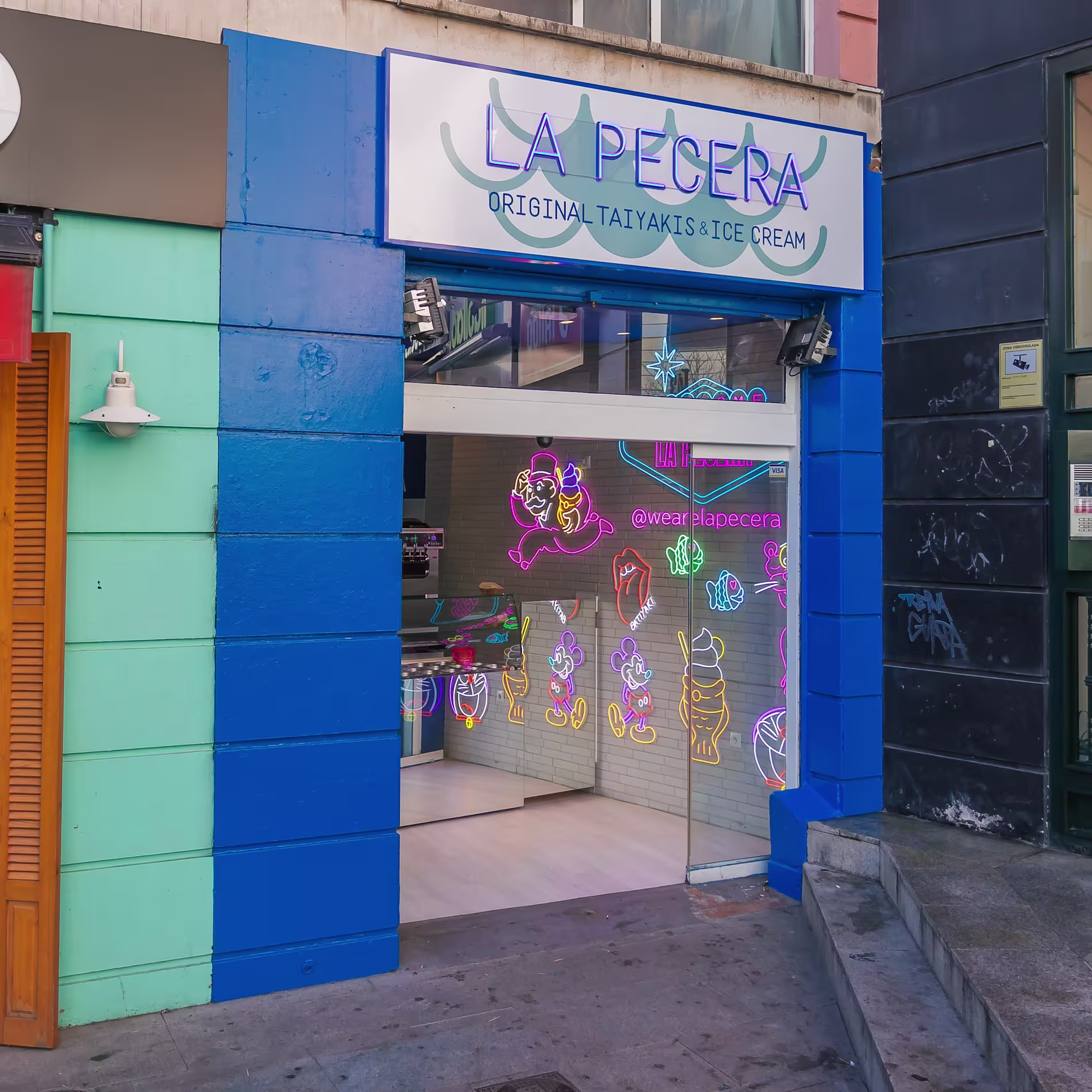 Fachada colorida de La Pecera Rafaella Carrà con neones vibrantes, cristaleras abiertas y estética pop asiática desde el primer vistazo.