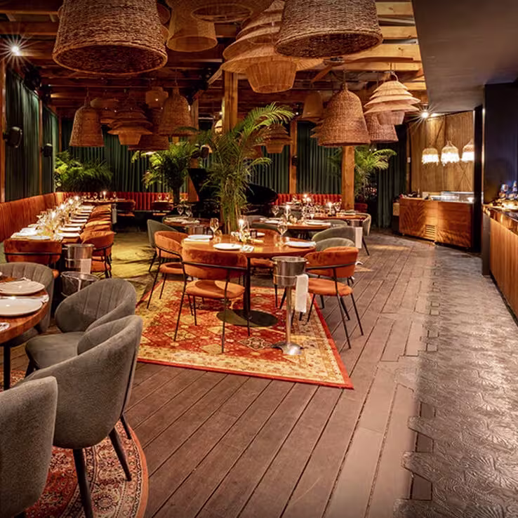 Ambiente cálido y sofisticado bajo lámparas artesanales y alfombras elegantes en Maquiavelo, donde la cena se convierte en una experiencia sensorial completa.