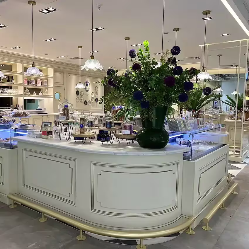 La barra del Café Bistrot Isabel Maestre brilla con vitrinas iluminadas, flores frescas y una cuidada estética clásica con molduras, dorados y lámparas colgantes.
