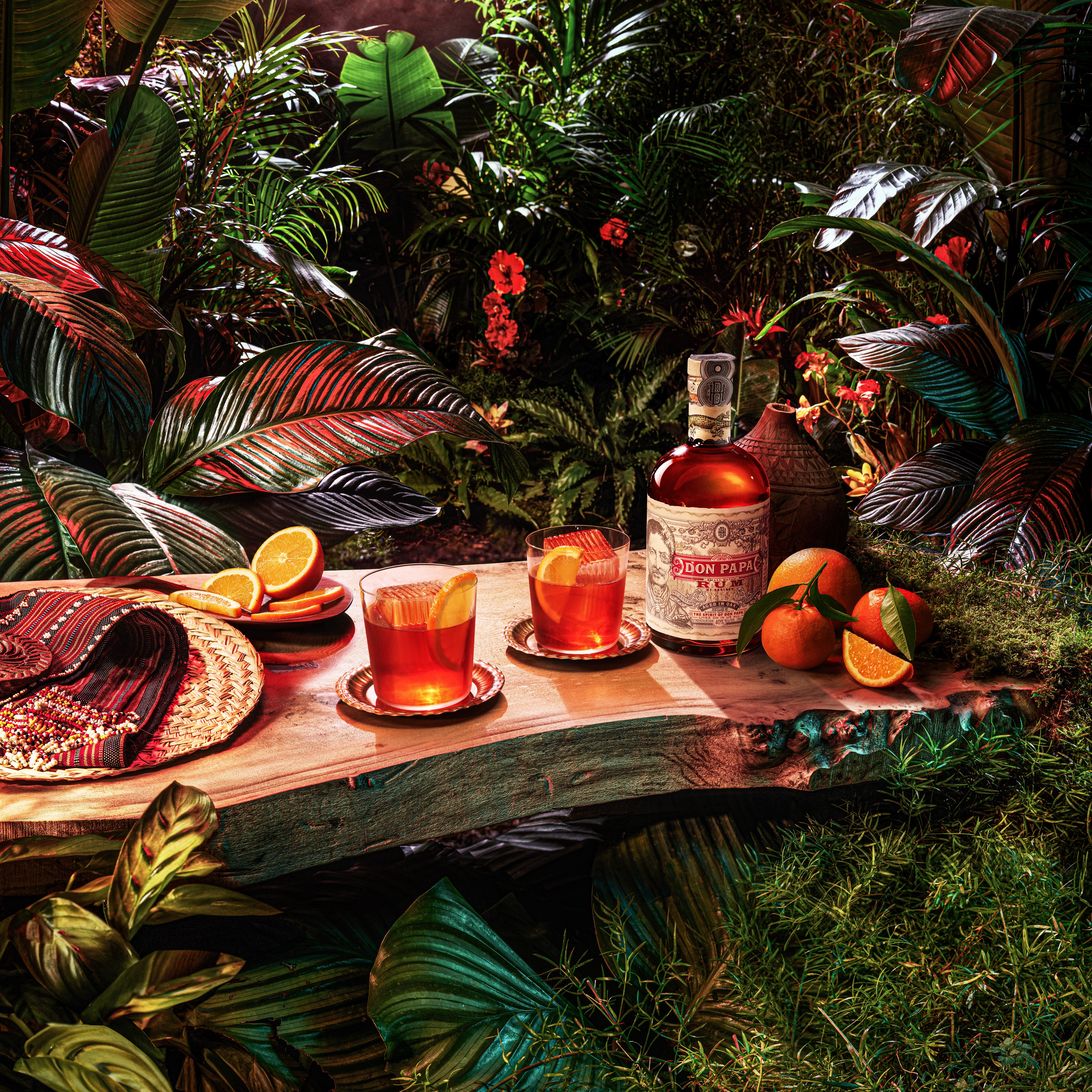 Două cocktailuri negroni Don Papa pe un fundal tropical.