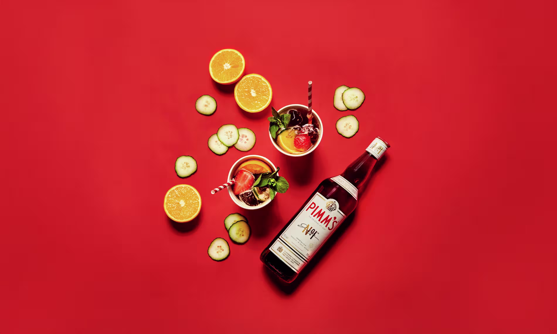 Pimm’s No.1 Cup bottle with two drinks and fruits sliced around it
