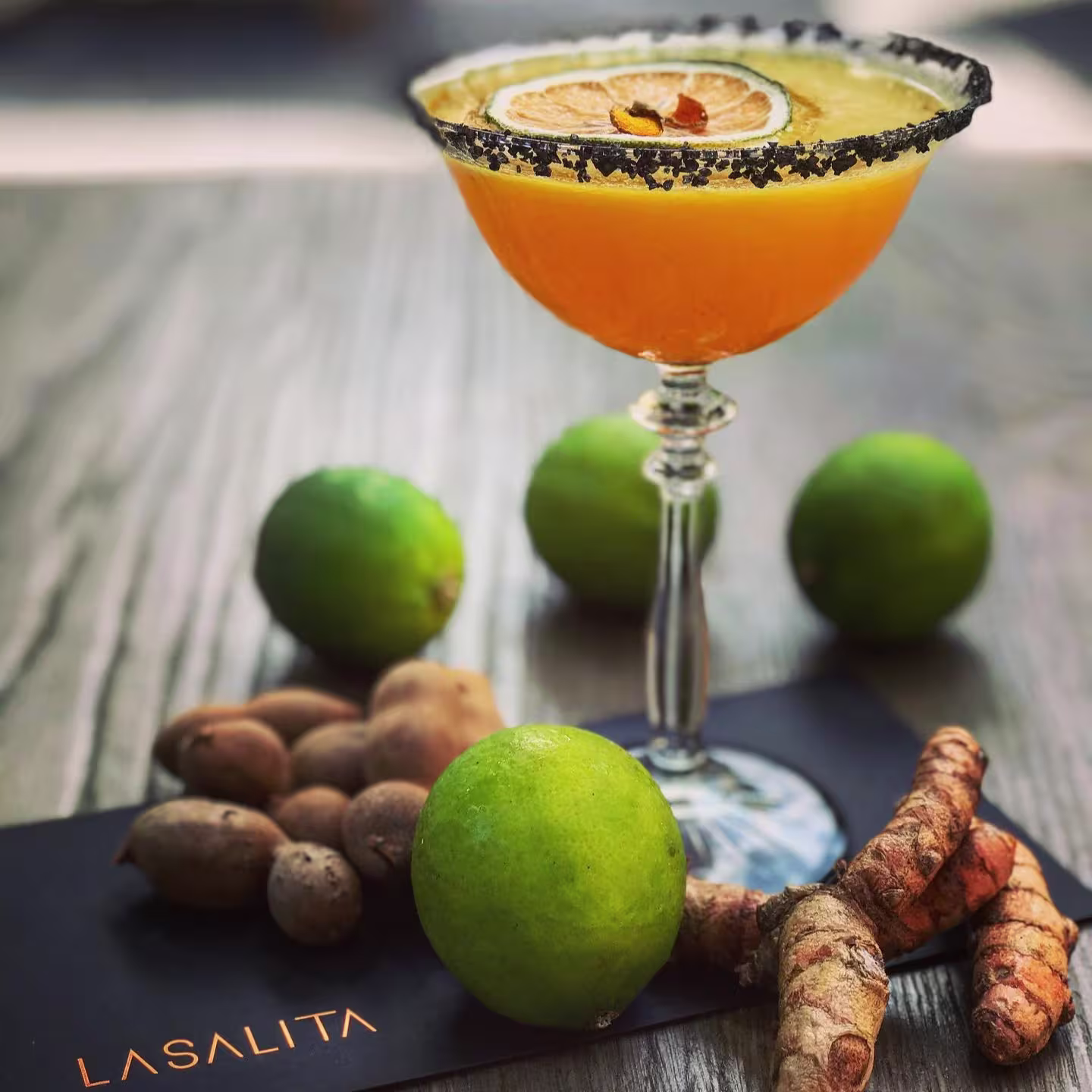 Un cóctel cítrico con sal negra en el borde brilla en la mesa de Cooktl by La Salita, rodeado de lima, cúrcuma y tamarindo como guiño a su esencia botánica.