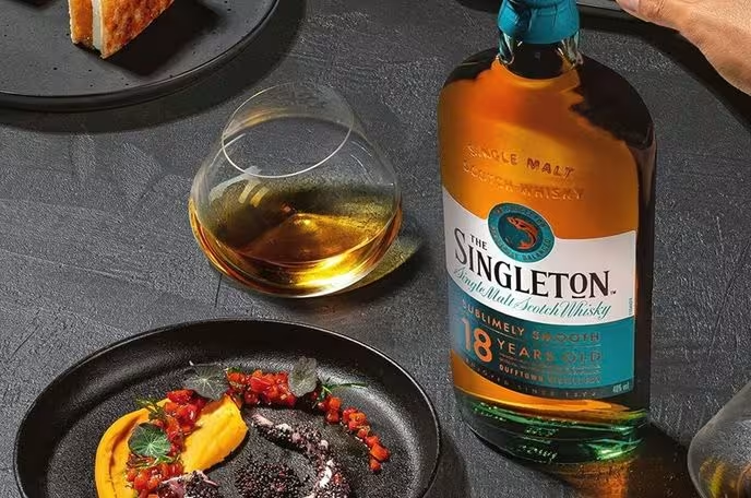 A balloon-style whisky glass filled with The Singleton 18 Year Old single malt Scotch whisky alongside a plate of fruit garnishes