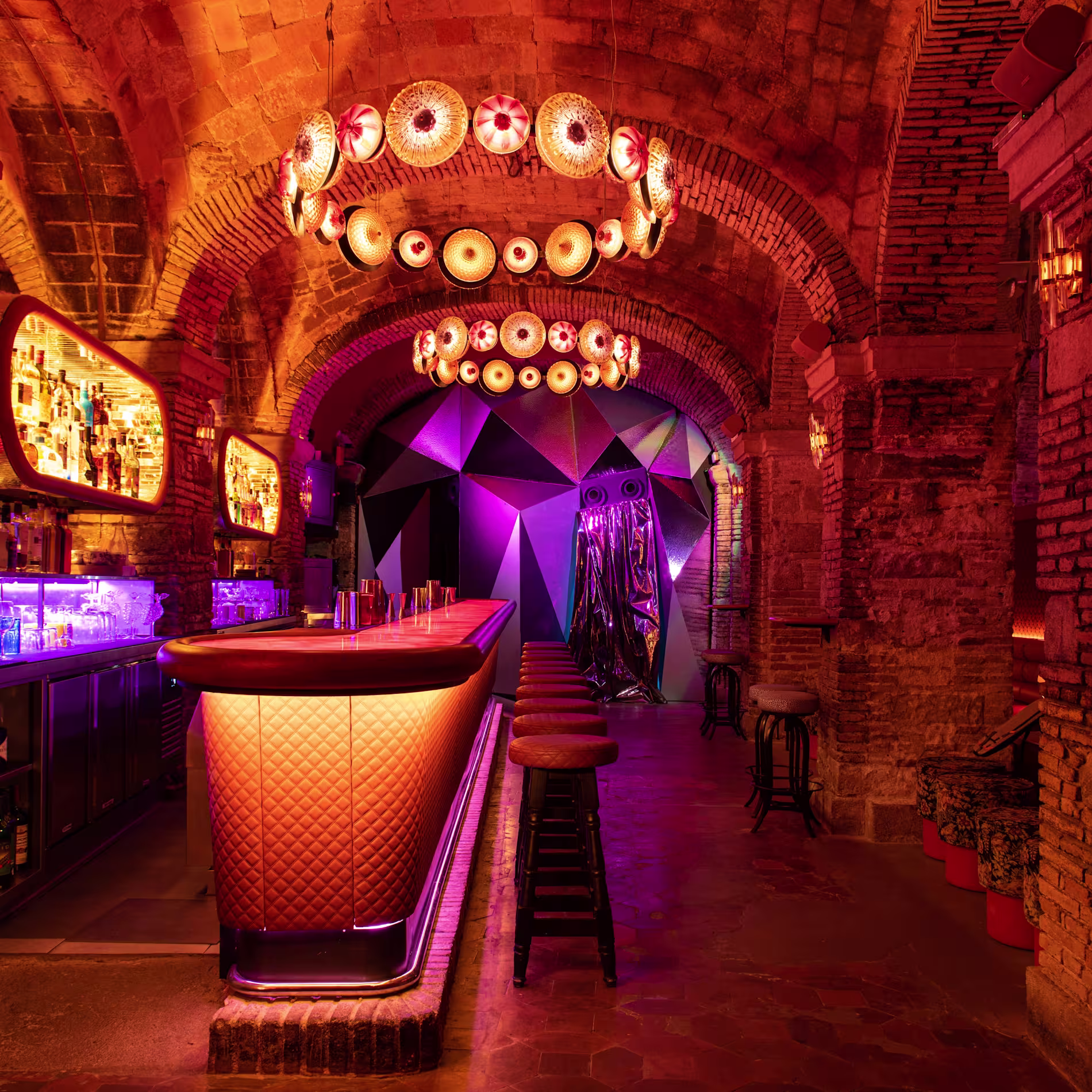 Monk combina arcos de ladrillo, luces cálidas y una barra futurista en un espacio íntimo, ideal para cócteles y noches exclusivas.