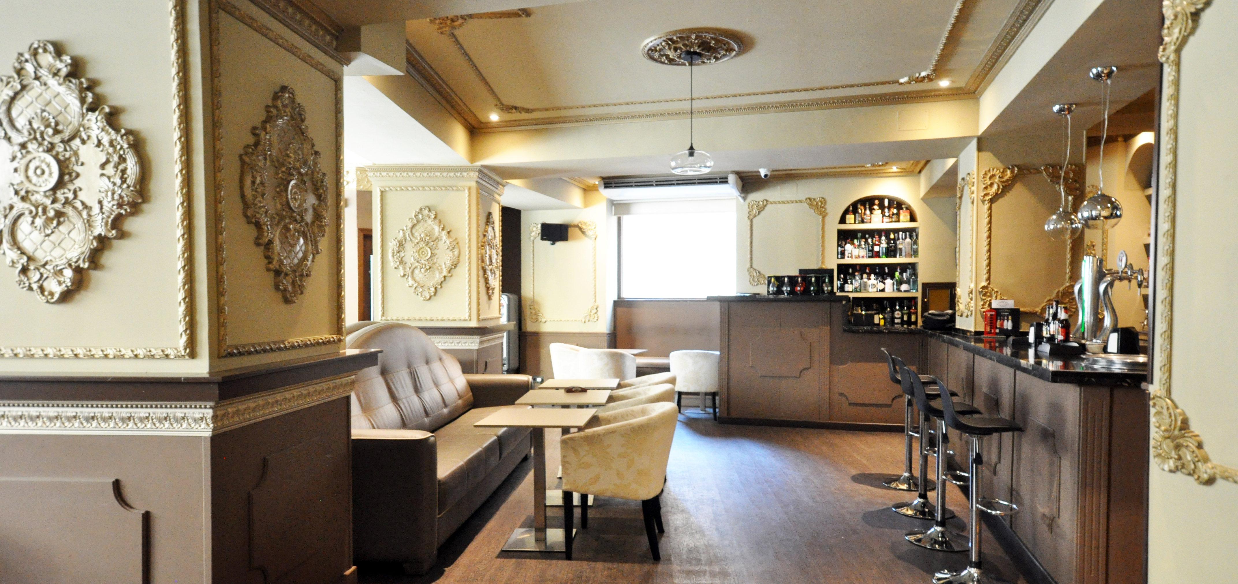 The New Salon del Café: elegante restaurante de estilo clásico y moderno, con detalles dorados en columnas y lámparas colgantes de cobre. Ambiente cálido y sofisticado.