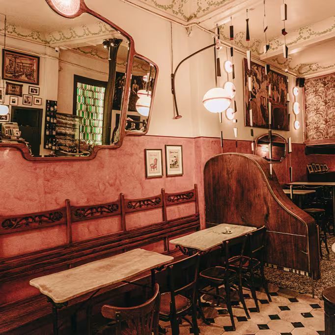 Cafè del Centre de esencia modernista con espejos ornamentales, bancos de madera y una atmósfera cálida que evoca la historia del local.