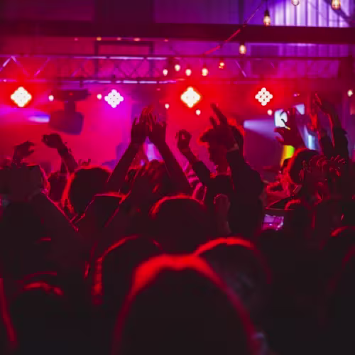 Platea: Un espacio vibrante donde la música y las luces rojas envuelven a la multitud en una atmósfera de energía. Perfecto para disfrutar de una noche llena de ritmo y diversión.